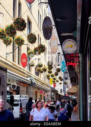 Melbourne, Victoria, Australia. 9 dicembre 2025. - I pedoni navigano in una vivace viuzza della città, fiancheggiata da negozi unici, ristoranti e adornata con nu Foto Stock