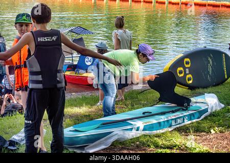 La gente prepara una barca per il surf SUP sul lago in estate: Abakan, Russia - 8 giugno 2024 Foto Stock