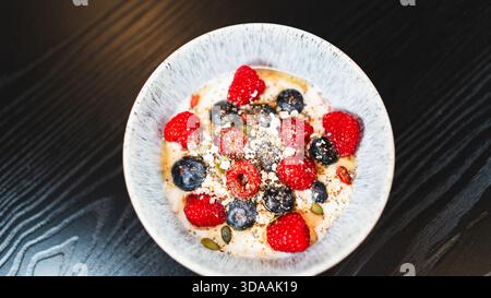 Sana ciotola di yogurt con lamponi e mirtilli freschi. Colazione o spuntino nutriente e ricco di antiossidanti per uno stile di vita attivo ed equilibrato Foto Stock
