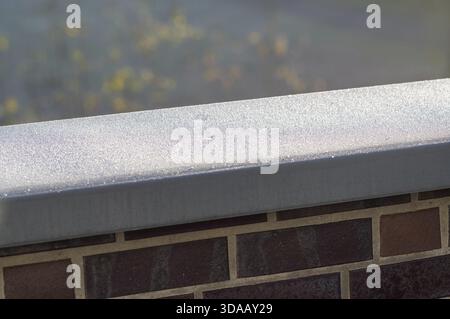 Borken, NRW, Germania, cristalli di ghiaccio che coprono una ringhiera metallica con una parete in mattoni e sfondo sfocato Foto Stock