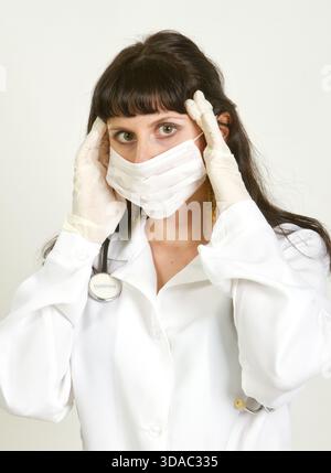 Medico donna esausta con mal di testa isolato su sfondo bianco Foto Stock