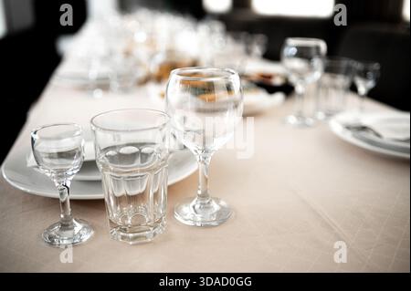 Ristorante. Un tavolo per cena. Posate, bicchieri e tovaglioli su un tavolo ricoperto da una tovaglia bianca Foto Stock