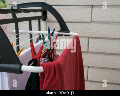 Vestiti appena lavati appesi sul balcone, fissati con appoggi, asciugati alla luce del sole e con una leggera brezza Foto Stock