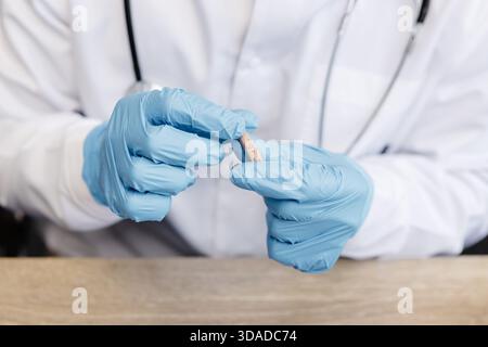 Un otolaringologo tiene in mano un apparecchio acustico. Il medico consulta il paziente. Foto Stock