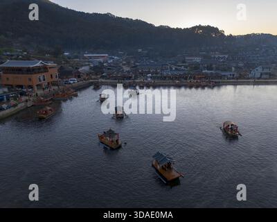 Serena vista aerea delle barche tradizionali sulle acque calme del tranquillo porto. bellissimo villaggio costiero annidato ai piedi della montagna durante il tranquillo tramonto Foto Stock