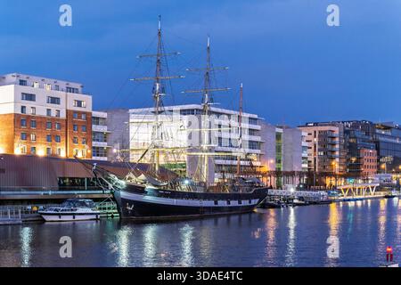 Nave alta ormeggiata nei Docklands di Dublino, storica nave marittima con alberi e attrezzature contro i moderni edifici di uffici. Foto Stock