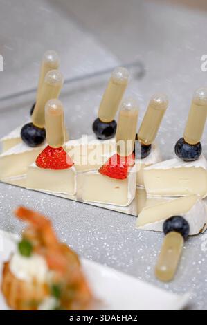 Formaggio Brie a pezzetti con fragole, uva e miele in pipette. Cucina molecolare e spuntini moderni con formaggio e pipette ripiene di salsa o h Foto Stock