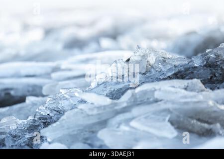 Un dettagliato primo piano di cristalli ghiacciati con sabbia all'interno su una superficie fredda e blu, che cattura la consistenza e l'umore invernale calmo per la natura, il tempo o il colon Foto Stock