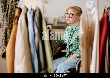 Ritratto di una giovane donna adulta che usa la sedia a rotelle per acquistare vestiti Foto Stock