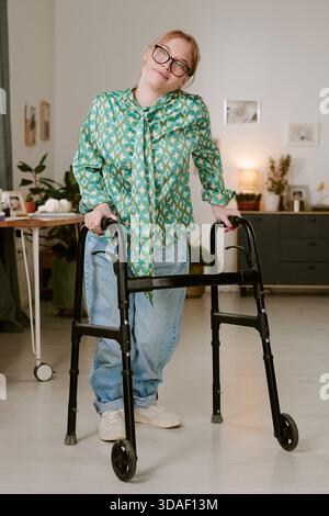 Ritratto di Young Woman che usa Walker e sorride in casa Foto Stock
