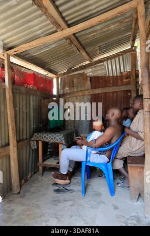 Adulti e bambini che giocano ai videogiochi all'interno della "sala videogiochi" di Macuti, sull'isola del Mozambico, Mozambico Foto Stock