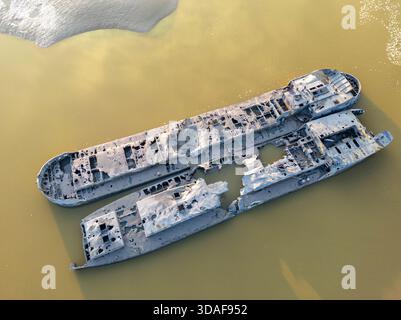 Vista aerea di relitti in rovina che riposano nelle acque torbide, resti spettrali contro il letto del fiume ocra, fiume Severn, Gloucestershire, Inghilterra. Foto Stock