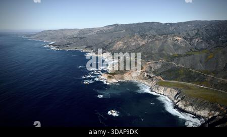 Veduta aerea dell'iconico Bixby Creek Bridge aggrappato alle aspre scogliere, mentre le onde azzurre si infrangono contro la costa, Big Sur, California, Stati Uniti Foto Stock