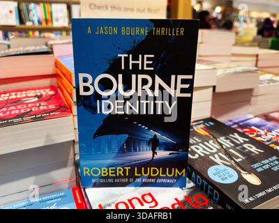 Manchester, Regno Unito - 15 novembre 2025: Una copertina di un thriller blu tratto da un romanzo più venduto esposto tra gli scaffali di una libreria affollata. Foto Stock