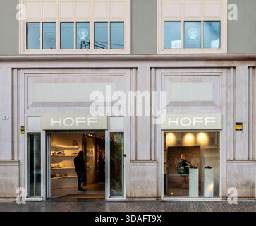 Negozio di scarpe HOFF esterno con grandi finestre, Malaga, Spagna. Espositore di scarpe e accessori, singolo cliente all'interno. Facciata in pietra di stile moderno. Foto Stock
