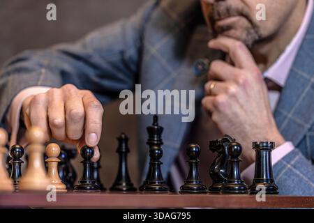 Mano maschile che muove il pezzo degli scacchi a bordo, primo piano Foto Stock