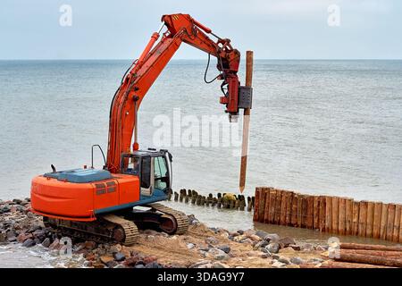 Una macchina per la guida di frantumazioni in legno sulla riva del mare Foto Stock