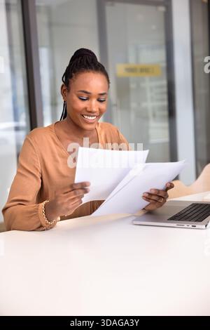 Giovane donna professionale nera che legge documenti Foto Stock