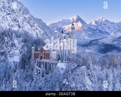 Castello di Neuschwanstein immerso nella neve, circondato da montagne innevate e foreste. Paesaggio invernale da favola, Schwangau vicino a Fuessen, Ostallgae Foto Stock