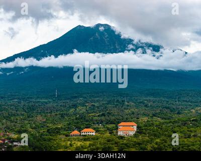 Vista panoramica di un villaggio tropicale e della foresta con il maestoso Monte Agung alle spalle Foto Stock