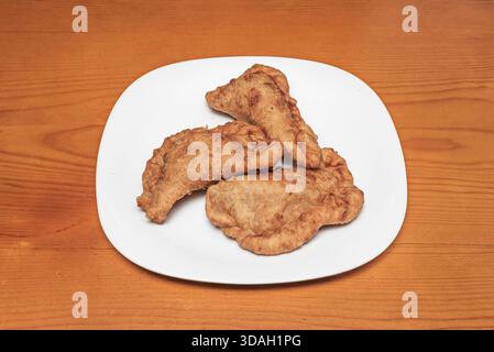 Diverse grandi empanadas al forno, con impasto croccante e il caratteristico bordo ondulato, rivelando il loro ripieno di tonno, pepe e pomodoro Foto Stock