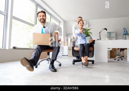 Gli uomini d'affari con scatole imballate che si divertono e puntano a qualcosa in ufficio il giorno in cui si muovono Foto Stock