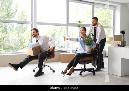 Gli uomini d'affari con scatole imballate che si divertono e puntano a qualcosa in ufficio il giorno in cui si muovono Foto Stock