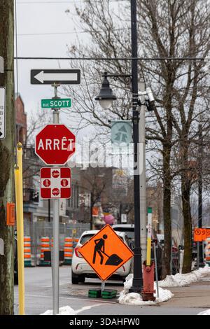 Canada, Quebec, 27 novembre 2025: Incrocio stradale con segnale di stop, avviso di costruzione, freccia direzionale, neve. Foto Stock