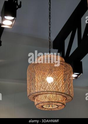 Luce calda e accogliente dalla lampada a sospensione intrecciata sul soffitto. elegante design degli interni e arredamento rustico che creano un'atmosfera invitante e d'atmosfera Foto Stock