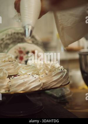 Meringhe per decorare a mano con sacchetto per pasticceria: Primo piano verticale, maniche eleganti, piatti vintage Foto Stock