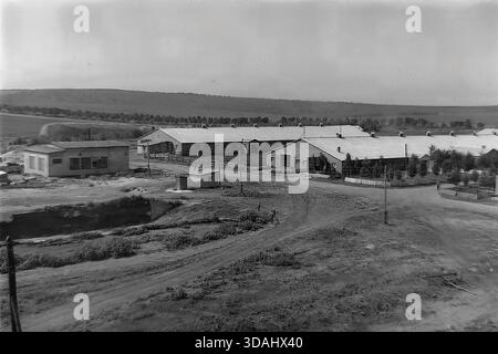 Bohorodychne, regione di Donetsk, RSS Ucraina, anni 1970 Una vista panoramica archivistica di un grande complesso agrituristico situato in una valle vicino alle colline. Lunghe stalle in mattoni e stalle con tetti in ardesia sono disposte intorno a cortili di sterrato. In primo piano, i cavalli sono visti in coralli di legno, mentre i materiali da costruzione suggeriscono lo sviluppo continuo delle infrastrutture rurali. Questo paesaggio cattura le dimensioni dell'allevamento e l'atmosfera tranquilla della campagna sovietica nel Donbas. Foto Stock