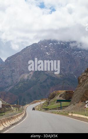 Regione di Naryn, Kirghizistan - 13 maggio 2024: Autostrada che si estende verso l'impressionante catena montuosa rocciosa nel Kirghizistan meridionale Foto Stock