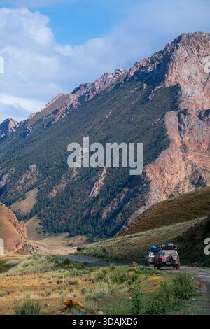 Regione di Naryn, Kirghizistan - 13 maggio 2024: I veicoli fuoristrada percorrono una pista sterrata vicino alle aspre montagne Foto Stock