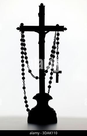 Sagoma di perline di crocifisso e rosario, simboli di fede, devozione e preghiera silenziosa: La speranza cristiana dura. Foto Stock