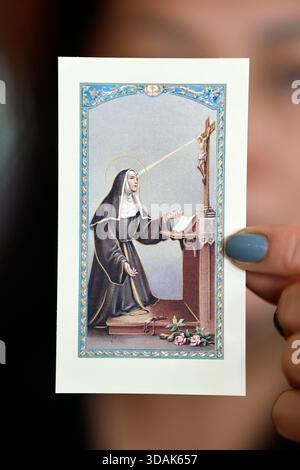 Fede e spiritualità. Donna cattolica con un'immagine religiosa in mano. Santa Rita di Cascia è la patrona delle vittime di abusi, delle coppie e del marr Foto Stock