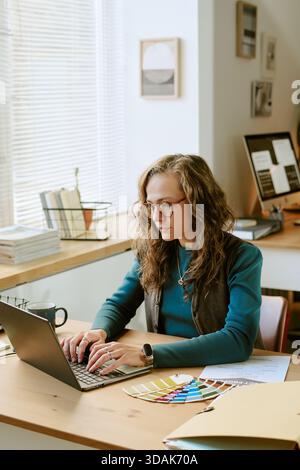 Giovane donna caucasica che lavora su un laptop in un ambiente moderno di Home Office Foto Stock