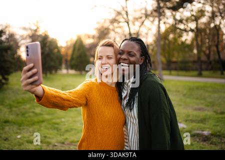 Diverse donne e amiche ridono scattando selfie al parco Foto Stock