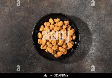 Stuzzichini di popcorn di pollo croccanti in una ciotola nera su sfondo grigio. Vista dall'alto. Menu fast food per spuntini di concetto Foto Stock