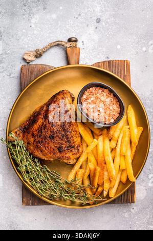 Grigliate coscia di pollo arrosto con frittura francese su un piatto, carne di pollame. sfondo grigio. vista dall'alto Foto Stock