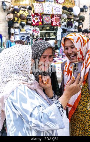 Donne sorridenti che guardano un cellulare a Bukhara, Uzbekistan Foto Stock