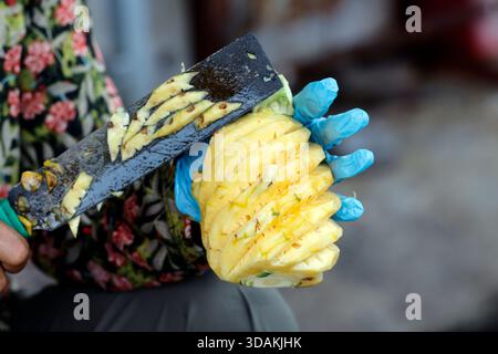 Cibo di strada. Donna che sbuccia un ananas. Vung Tau. Vietnam. Foto Stock