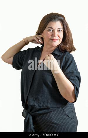 Donna sorridente mentre regola i capelli su uno sfondo chiaro. Foto Stock