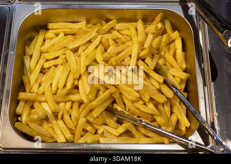 Vista ravvicinata di una grande quantità di patatine fritte fresche pronte per essere servite da un buffet o da un ristorante Foto Stock