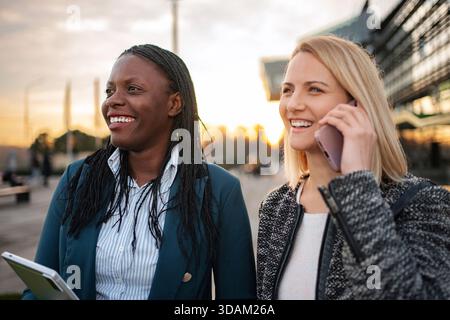 Diverse donne d'affari sorridenti che camminano utilizzando la tecnologia collaborando Foto Stock