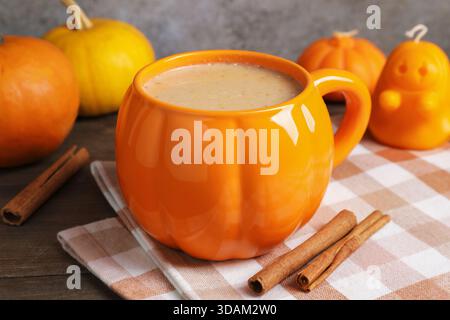 Latte di zucca caldo in tazza su un tavolo di legno, primo piano. Atmosfera autunnale Foto Stock
