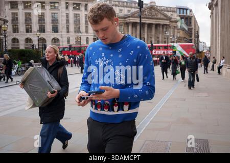 Con poche settimane prima di Natale, un operaio della City indossa un maglione festoso, andando a una festa d'ufficio nella City di Londra, il quartiere finanziario della capitale, l'11 dicembre 2025, a Londra, in Inghilterra. Foto Stock