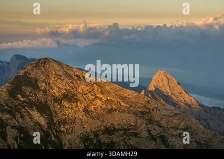 Vista aerea della luce del sole dorata che bacierà le aspre vette delle Alpi Giulie sotto una coperta di morbide nuvole, Tosc, Radovljica, Slovenia. Foto Stock