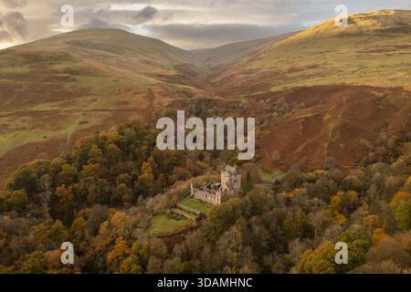 Vista aerea del Castello Campbell, immerso in una vibrante foresta autunnale, in contrasto con le ondulate colline ocra sotto un cielo nuvoloso, Dollar, Scotland, Unit Foto Stock