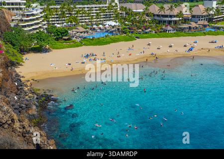 Vista aerea di una vivace spiaggia con acque turchesi che incontrano sabbia dorata, incorniciata da scogliere rocciose e lussuosi hotel, Lahaina, Hawaii, United Foto Stock