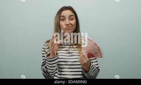 Donna che tiene in mano banconote della corona islandese con un'espressione riflessiva su sfondo bianco isolato, suggerendo decisioni finanziarie o denaro ma Foto Stock
